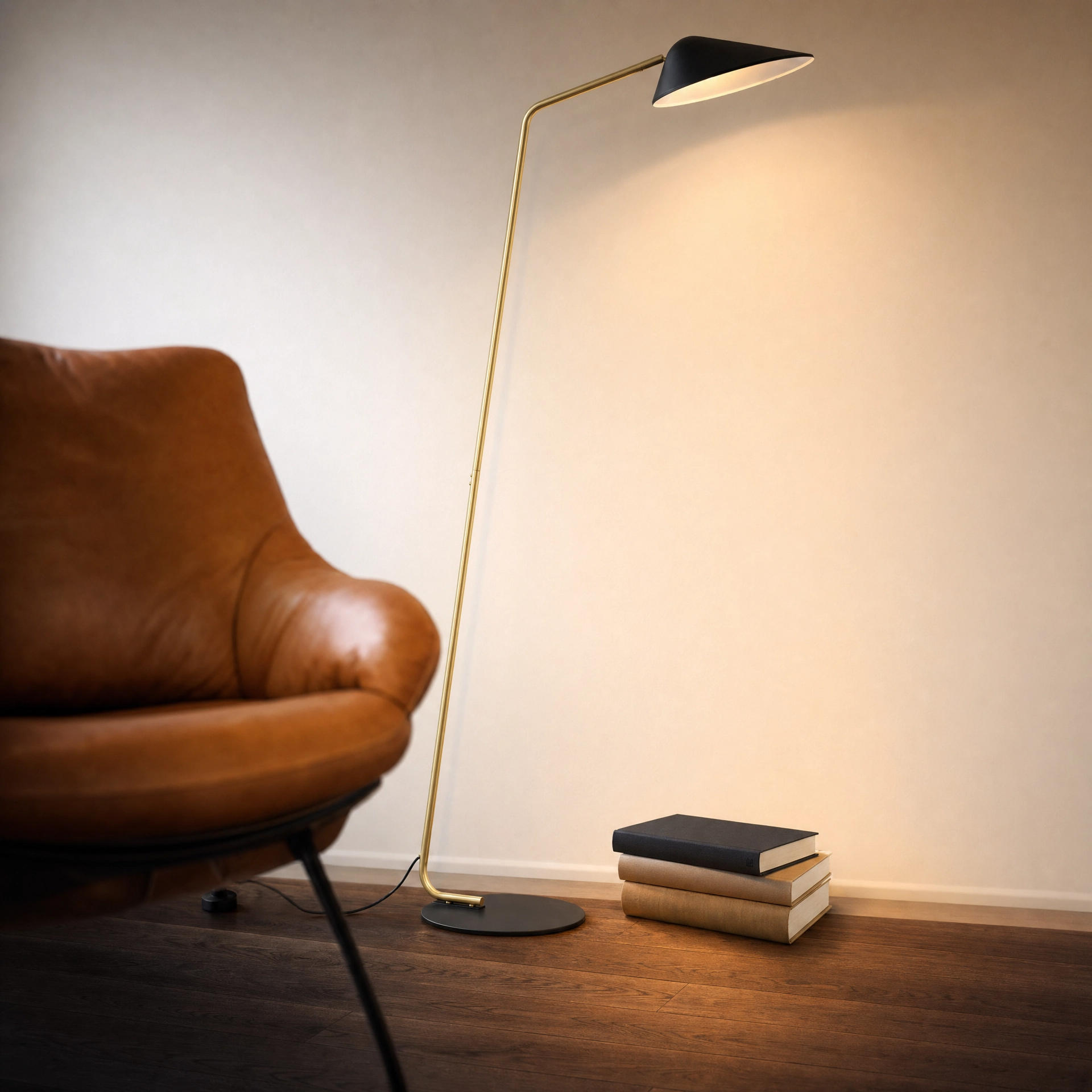 Beacon Swivel Arc Floor Lamp with satin brass rod and matte black shade beside a leather reading chair