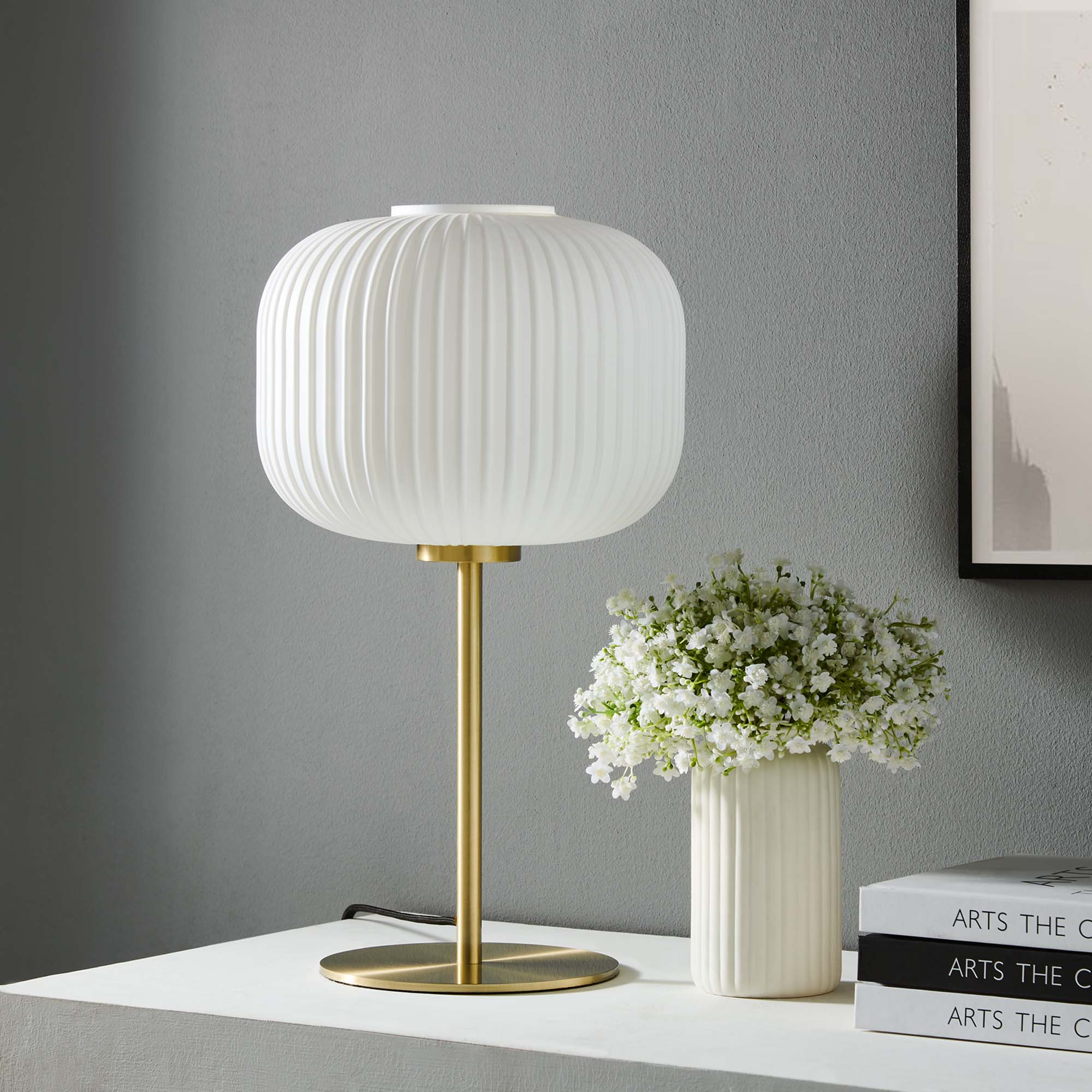 Reverie Ribbed Glass Sphere Table Lamp in White with satin brass stem and base on a white shelf